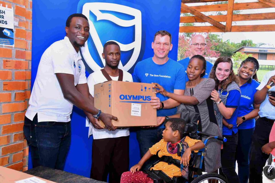 Tich Makonese the Stanbic Bank Head of Insurance handing over the part of assortment to the Gem Foundation team. 11zon